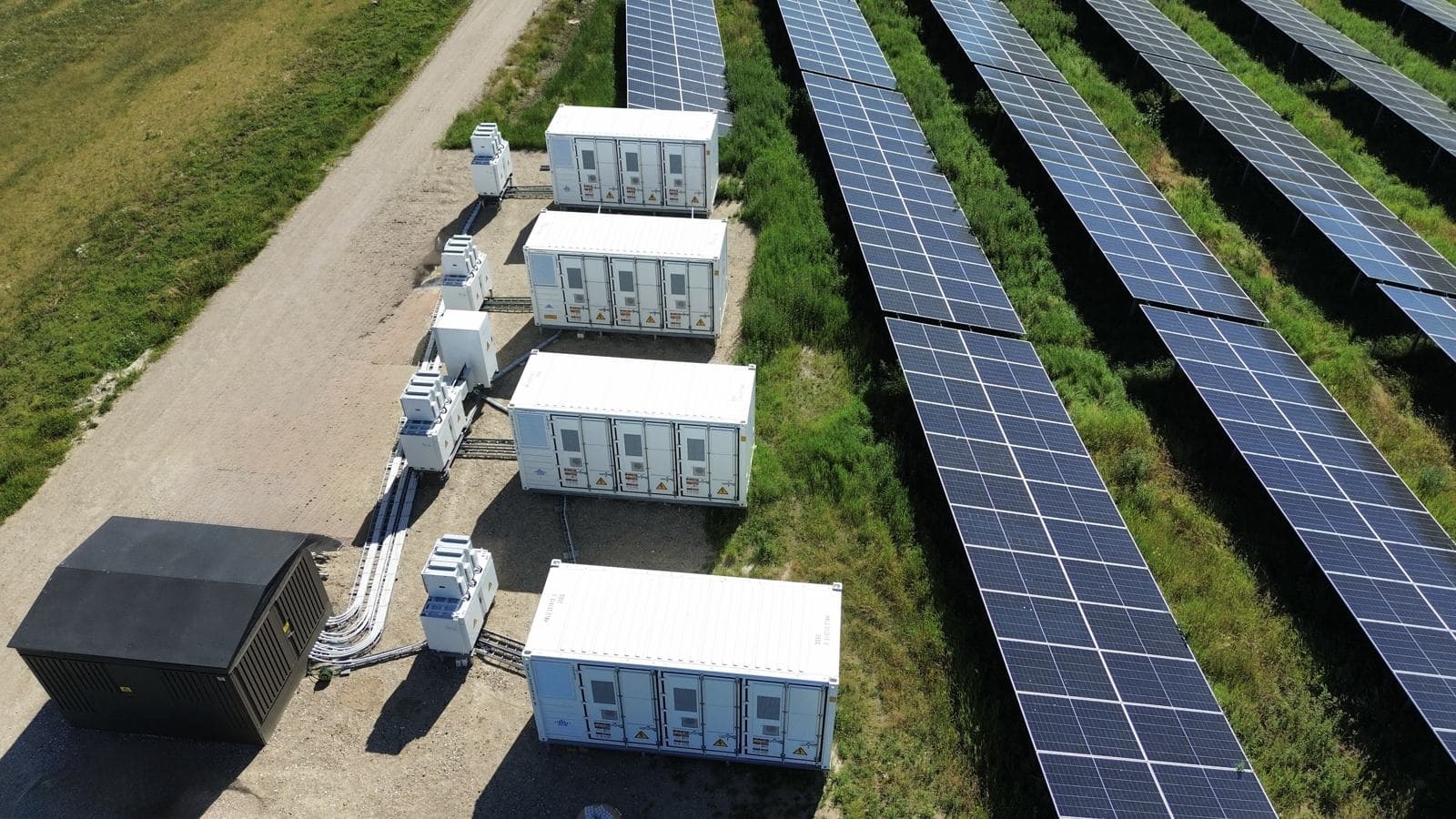 Solarpark mit Batteriespeicher-Containern, Trafostation und Kabeltrasse
